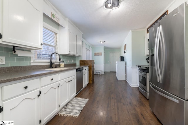 kitchen with dark wood-type flooring, a sink, stainless steel appliances, white cabinetry, and backsplash