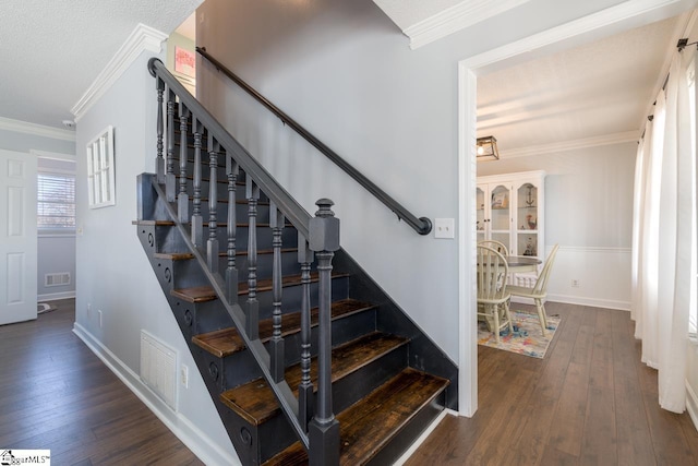 stairs with wood-type flooring, visible vents, and ornamental molding