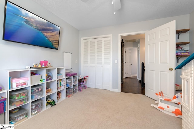 playroom featuring carpet flooring, ceiling fan, and a textured ceiling