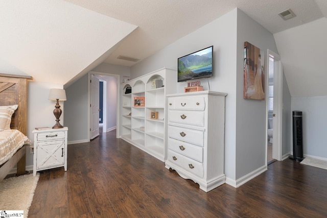 bedroom with a textured ceiling, visible vents, vaulted ceiling, and dark wood-type flooring