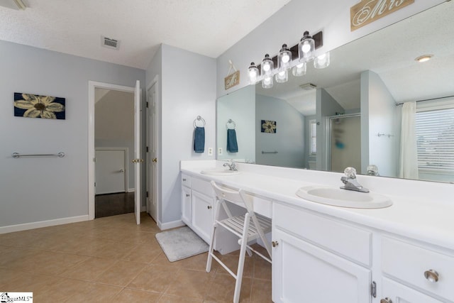 bathroom with double vanity, visible vents, a sink, a shower stall, and tile patterned flooring