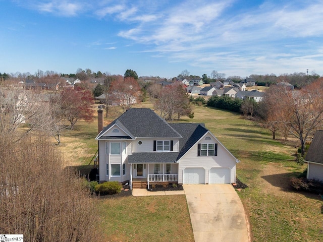 traditional-style house featuring covered porch, driveway, a front yard, and an attached garage