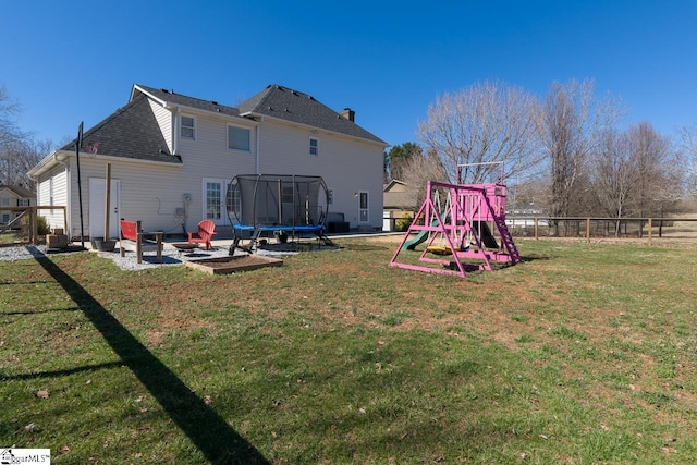 rear view of house featuring a trampoline, fence, a yard, a patio area, and a playground