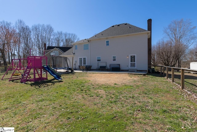 rear view of property featuring a patio, a chimney, fence, a yard, and a playground