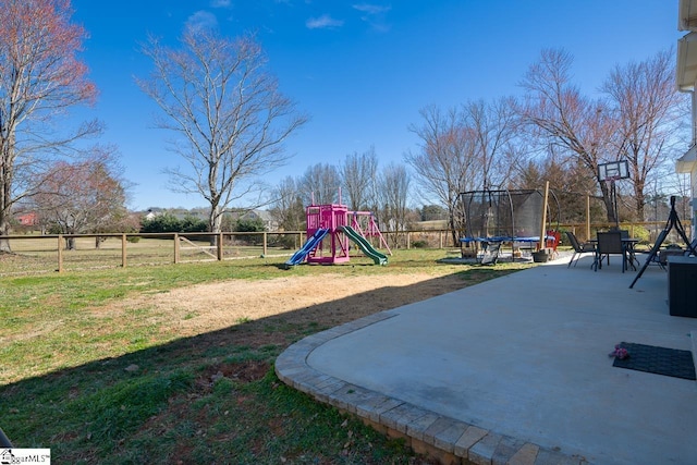 community playground featuring a fenced backyard, a trampoline, and a lawn