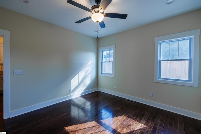 spare room with dark wood-style floors, visible vents, baseboards, and a ceiling fan