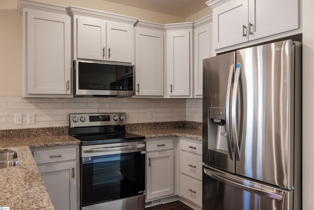 kitchen with stainless steel appliances, light stone counters, white cabinets, and decorative backsplash