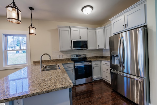 kitchen with tasteful backsplash, dark wood-style floors, appliances with stainless steel finishes, a peninsula, and a sink