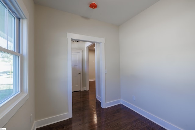 spare room with dark wood-style flooring and baseboards