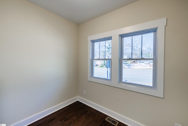 unfurnished room featuring dark wood-style floors, baseboards, and visible vents