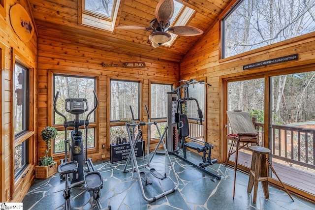 exercise room with a skylight, stone tile floors, wooden ceiling, wood walls, and high vaulted ceiling