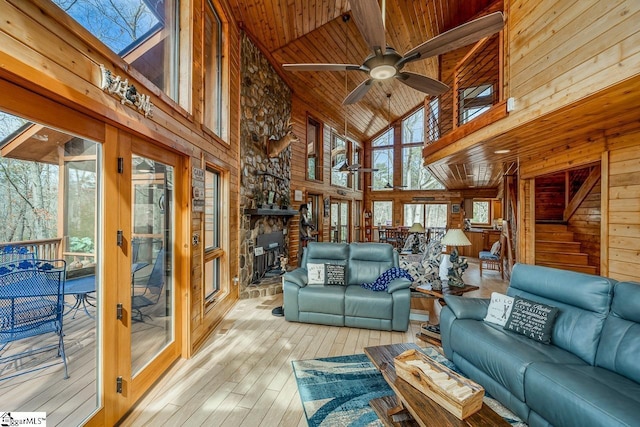 living room featuring lofted ceiling, wood ceiling, ceiling fan, wooden walls, and light wood-type flooring