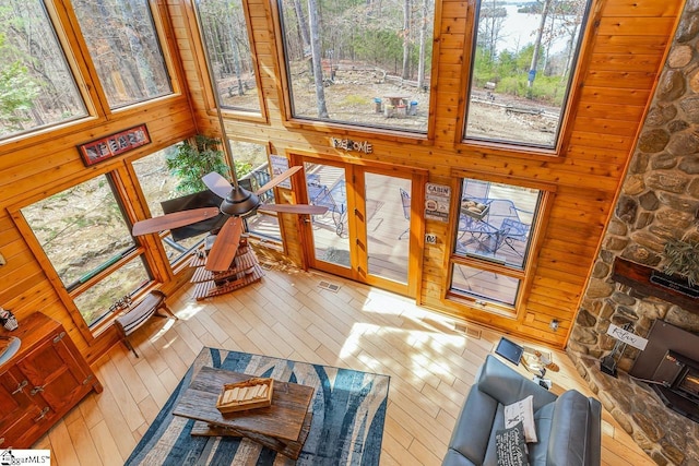 living area featuring wood walls, a high ceiling, visible vents, and a wealth of natural light