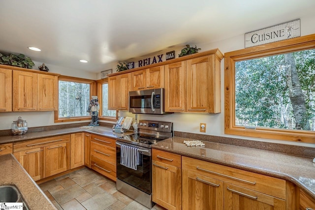 kitchen with dark stone countertops, stainless steel appliances, recessed lighting, and stone finish flooring