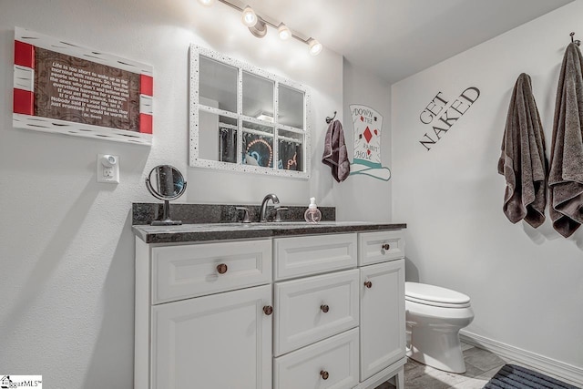 bathroom with baseboards, vanity, and toilet