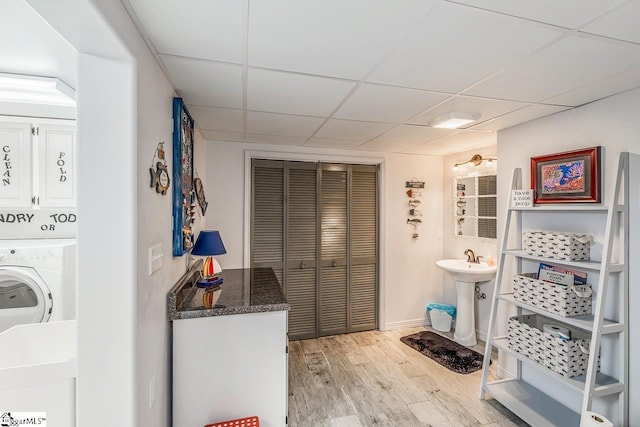 bathroom with a sink, wood finished floors, washer / dryer, a drop ceiling, and baseboards