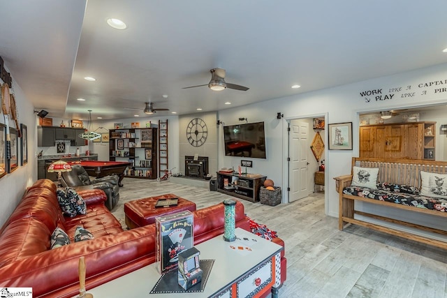 living room with light wood-type flooring, a wood stove, billiards, and recessed lighting