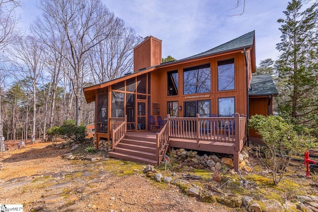 rear view of house featuring a sunroom, a chimney, and a deck