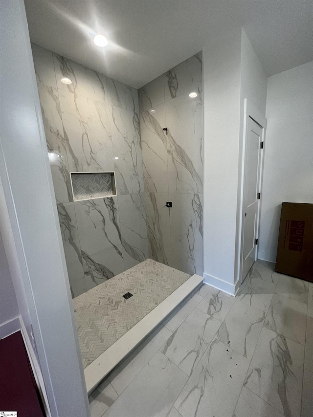 bathroom with marble finish floor, a marble finish shower, and baseboards