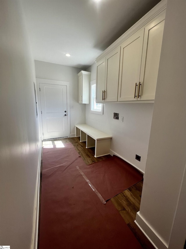 clothes washing area featuring dark wood-type flooring, cabinet space, and baseboards