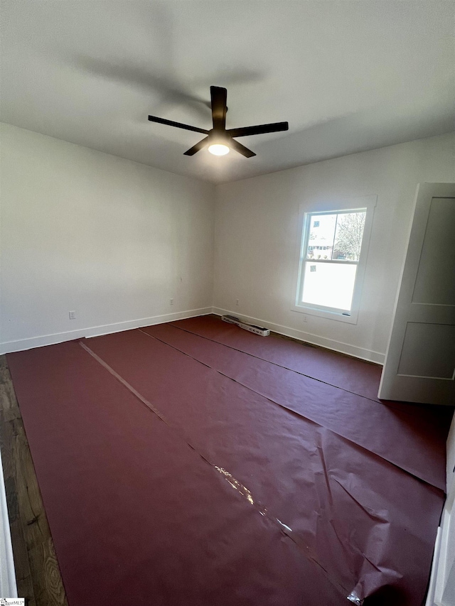 spare room featuring a ceiling fan and baseboards