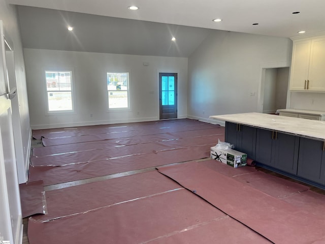 kitchen with recessed lighting, white cabinets, vaulted ceiling, and baseboards