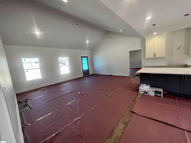 living area with recessed lighting, a healthy amount of sunlight, vaulted ceiling, and baseboards