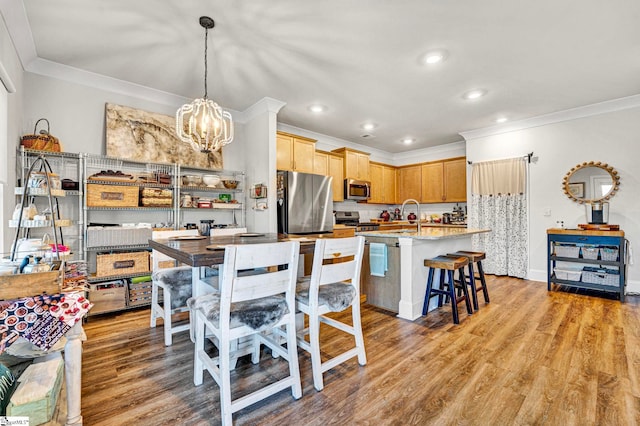 kitchen featuring a notable chandelier, stainless steel appliances, light countertops, light wood-style floors, and ornamental molding