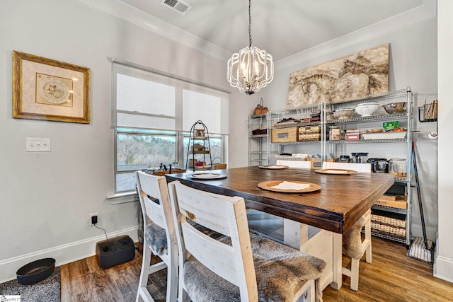 dining room with baseboards, wood finished floors, visible vents, and a notable chandelier