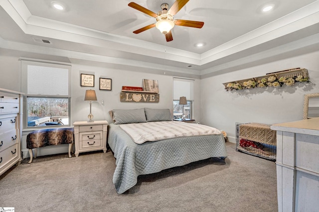 bedroom with light carpet, multiple windows, and a tray ceiling