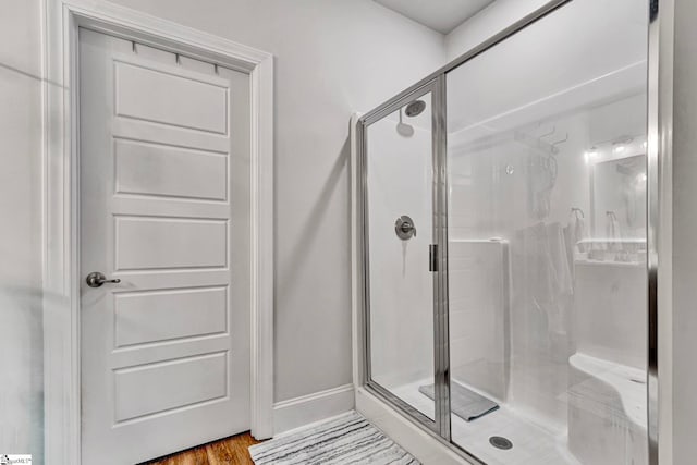 full bathroom featuring a stall shower, wood finished floors, and baseboards