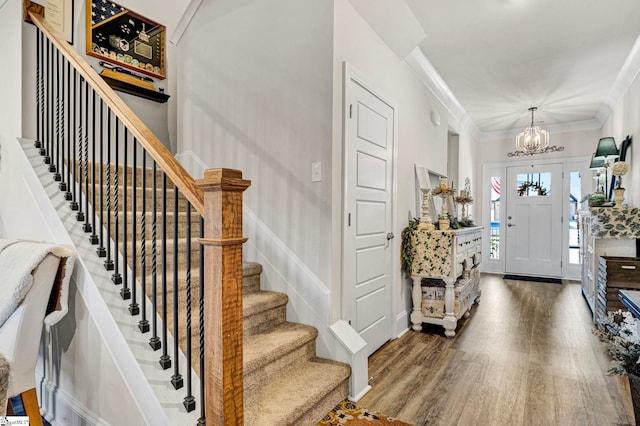 entrance foyer featuring crown molding, baseboards, a chandelier, and wood finished floors