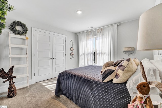 carpeted bedroom with visible vents and a closet