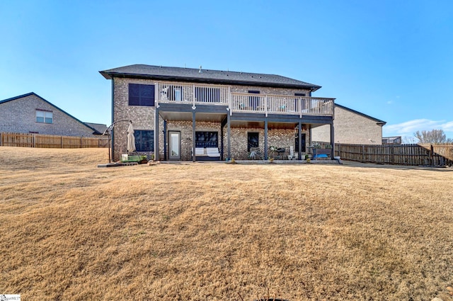 back of property featuring a balcony, fence, a lawn, and brick siding