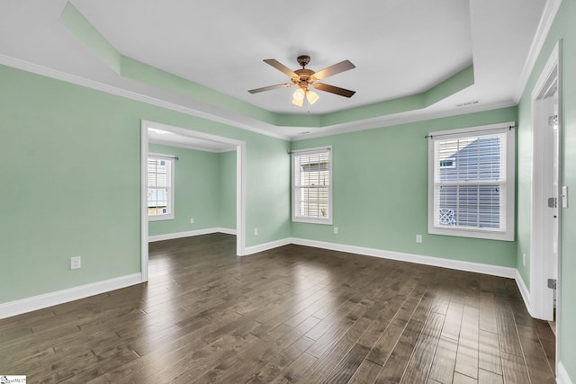 spare room featuring visible vents, a ceiling fan, baseboards, dark wood-style floors, and a tray ceiling