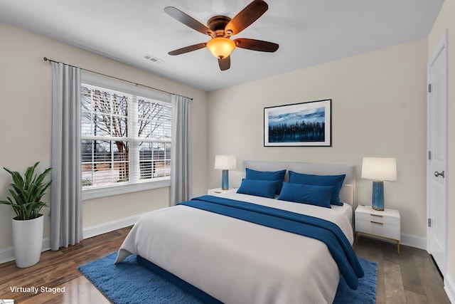 bedroom with ceiling fan, wood finished floors, visible vents, and baseboards