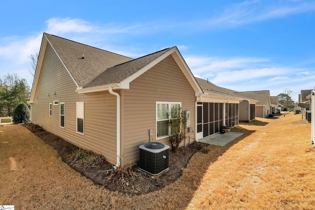 view of home's exterior with a shingled roof, cooling unit, and a yard