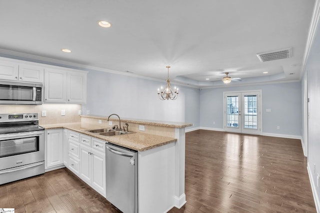 kitchen with stainless steel appliances, a peninsula, a sink, visible vents, and a raised ceiling