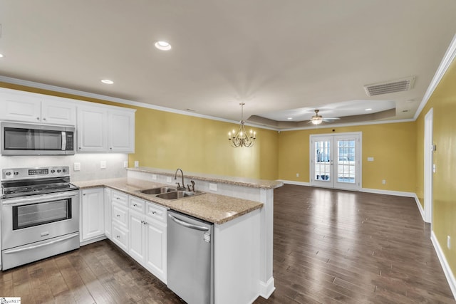 kitchen with visible vents, dark wood-style floors, a peninsula, stainless steel appliances, and a sink