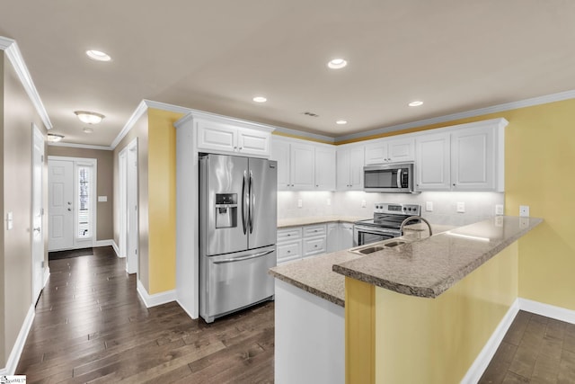 kitchen featuring ornamental molding, a peninsula, appliances with stainless steel finishes, and dark wood finished floors