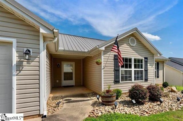 doorway to property featuring an attached garage, a standing seam roof, and metal roof