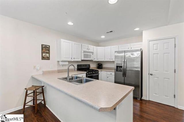 kitchen featuring white microwave, black gas range, a peninsula, a sink, and stainless steel refrigerator with ice dispenser