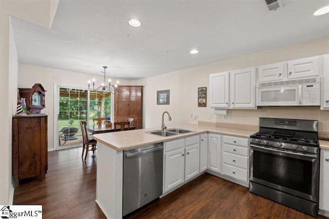 kitchen with a peninsula, white cabinetry, appliances with stainless steel finishes, and a sink