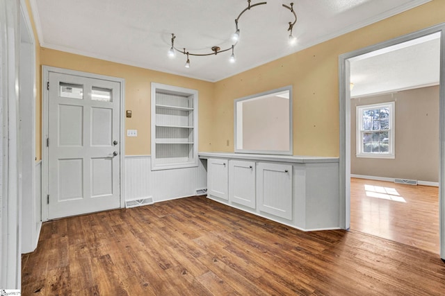 unfurnished dining area featuring crown molding, wood finished floors, visible vents, and built in features