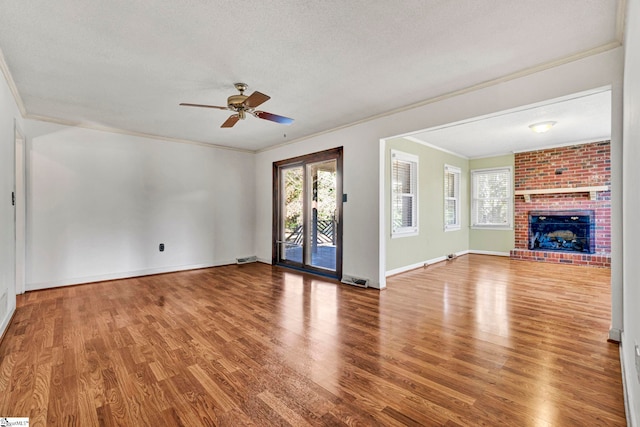 unfurnished living room featuring a textured ceiling, a brick fireplace, wood finished floors, and a healthy amount of sunlight