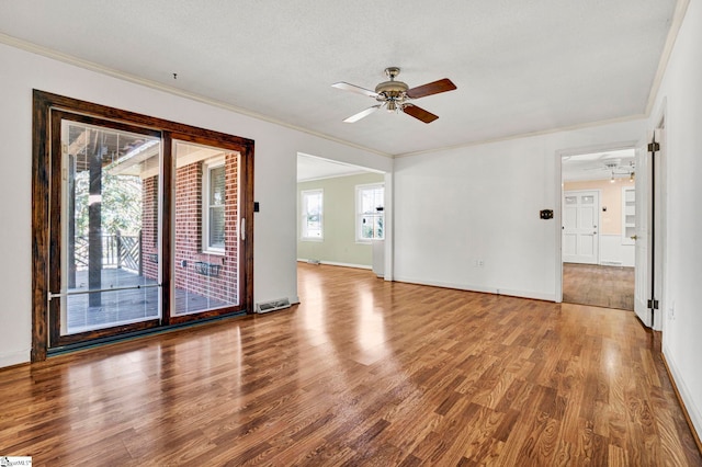 empty room featuring a ceiling fan, ornamental molding, and wood finished floors