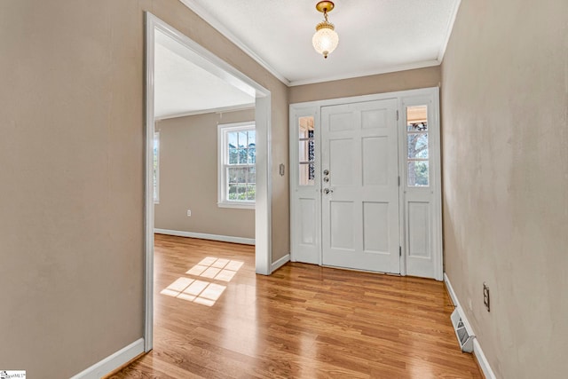 entryway featuring light wood-style floors, ornamental molding, and baseboards