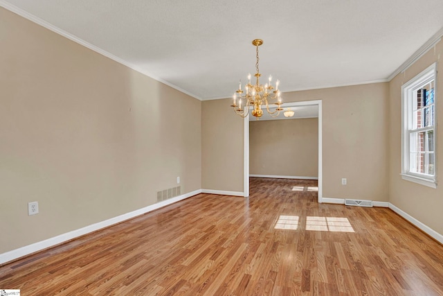 empty room featuring ornamental molding, light wood-style flooring, visible vents, and baseboards