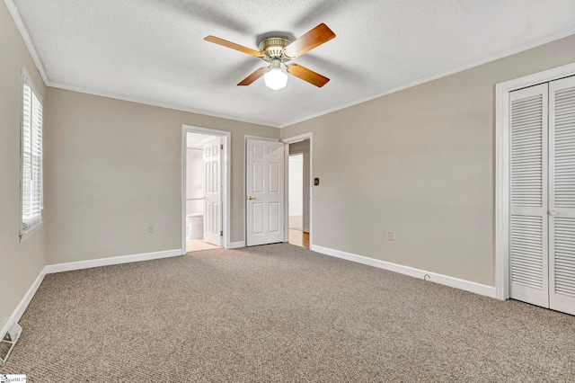 unfurnished bedroom featuring ornamental molding, carpet flooring, a textured ceiling, and multiple windows