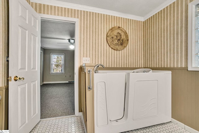 clothes washing area featuring a textured ceiling, a wainscoted wall, ornamental molding, independent washer and dryer, and wallpapered walls